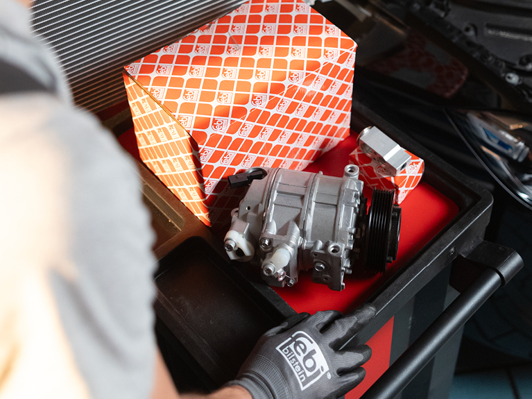 Mechanic's hands with febi boxes and A/C Parts on a trolley