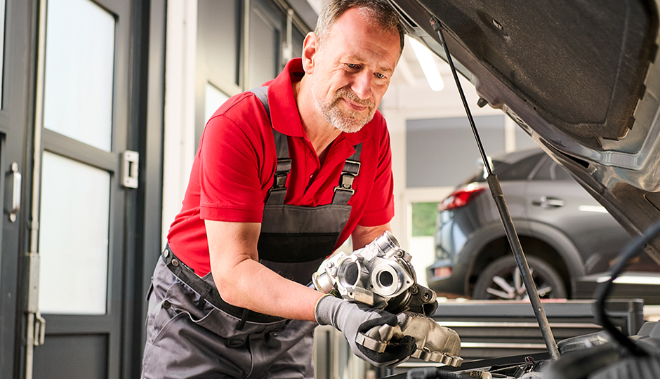 Mechanic holding turbocharger in a workshop