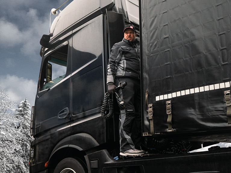 A mechanic in a workshop close to a semi-trailer